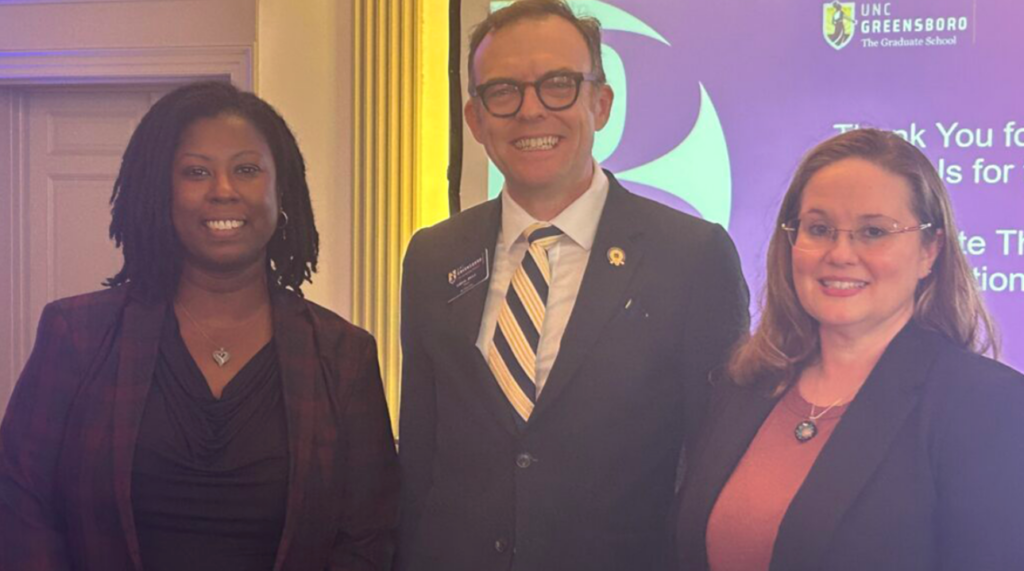 Two women and a man in blazers smile